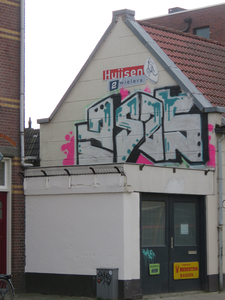 833339 Afbeelding van onlangs aangebrachte graffiti met een gestileerde tekst, op de zijgevel van de werkplaats van de ...